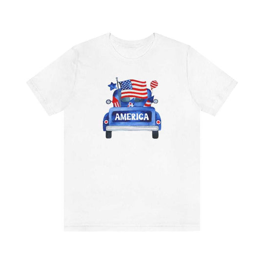 A classic America Truck Tee featuring a white shirt with a blue truck and flag design. Unisex jersey tee made of 100% cotton, with ribbed knit collar and taping for durability. Sizes XS to 3XL available.