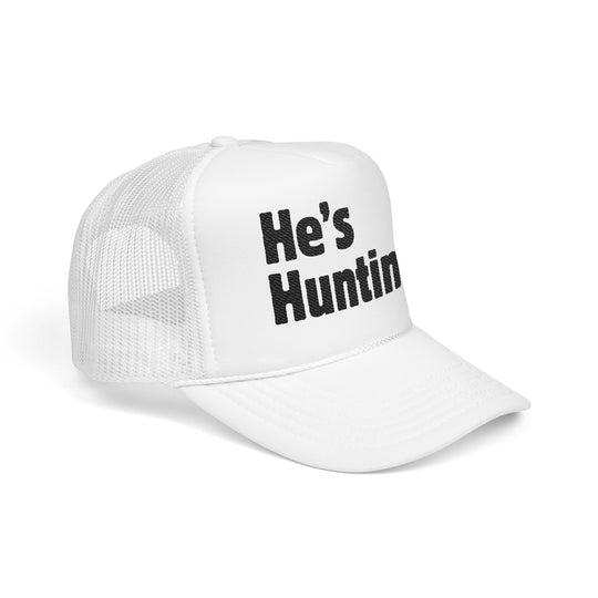 White trucker hat with He’s Huntin… in black on front foam panel, mesh back, curved brim, adjustable snap. Ideal for custom embroidery.