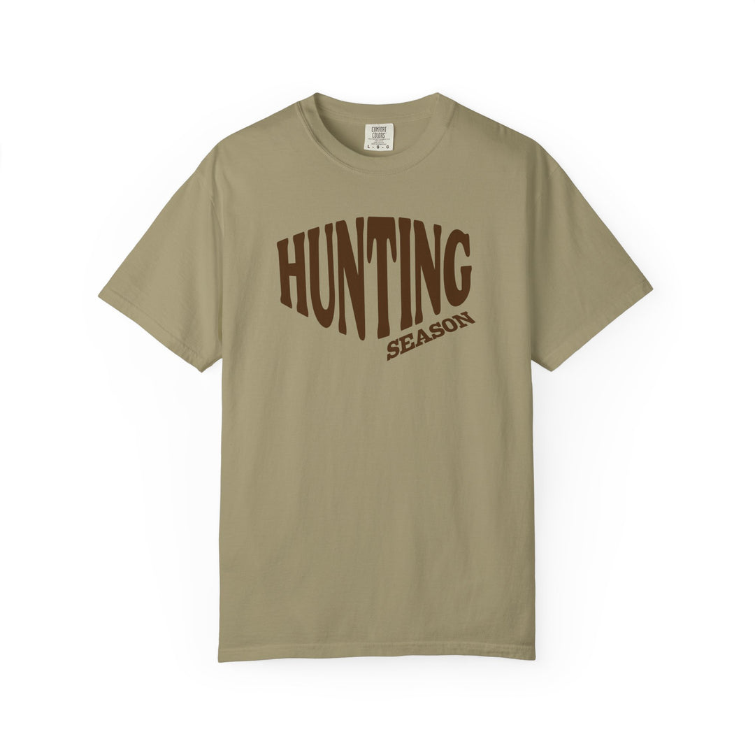 Hunting Season Tee in muted tan/olive, featuring large brown text, relaxed fit, and durable stitching. Ideal for casual wear, made from 100% ring-spun cotton.