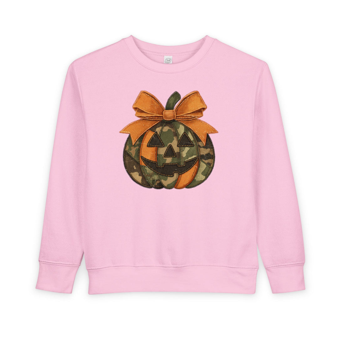 Jackie O Toddler Crew: Pink long-sleeve sweatshirt featuring a camo and orange jack-o’-lantern with a large bow, designed for warmth and comfort.