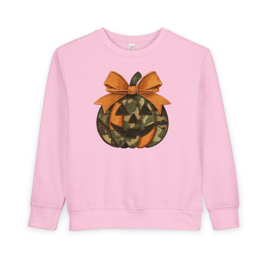 Jackie O Toddler Crew: Pink long-sleeve sweatshirt featuring a camo and orange jack-o’-lantern with a large bow, designed for warmth and comfort.