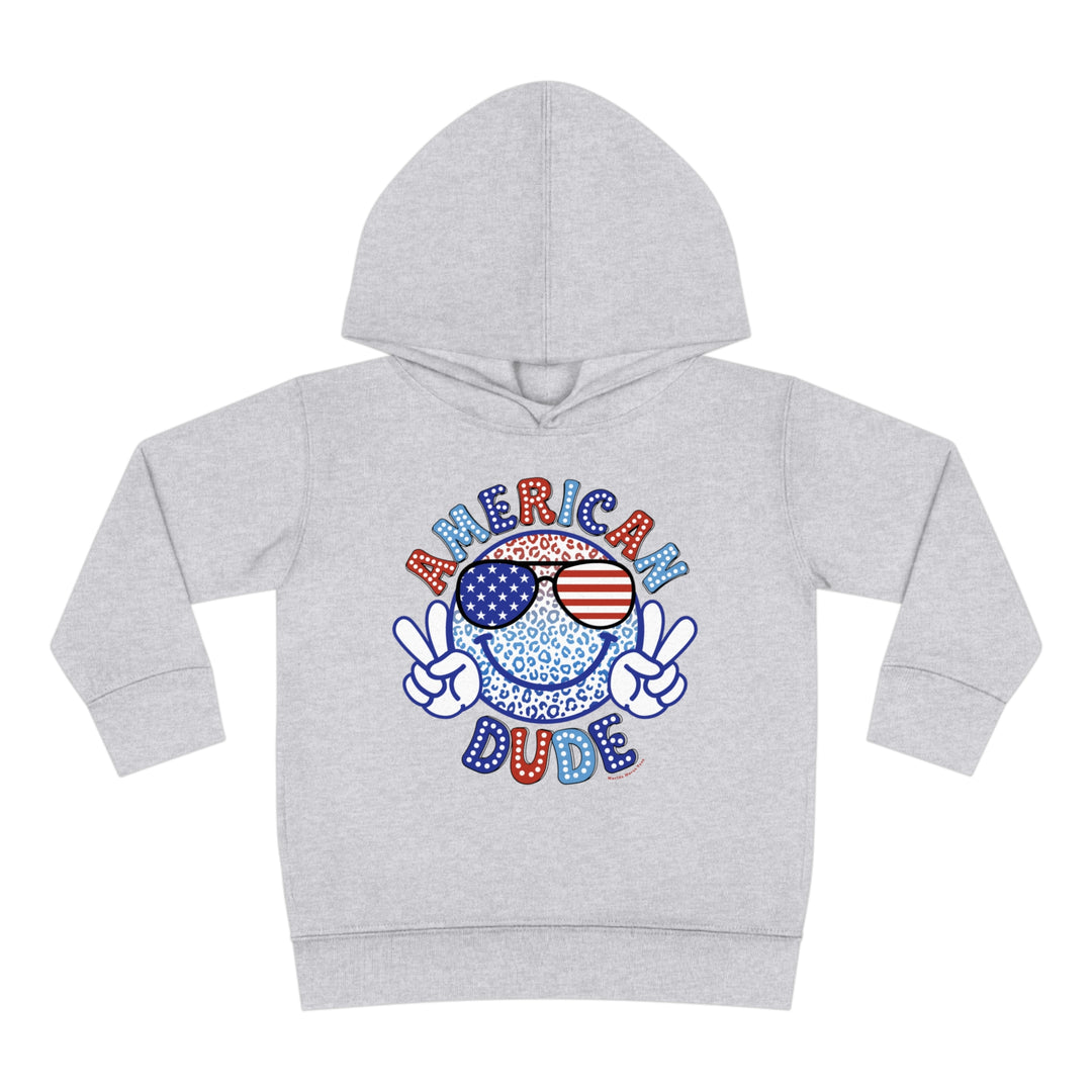 American Dude Toddler Hoodie featuring a smiley face with sunglasses design. Jersey-lined hood, cover-stitched details, and side seam pockets for durability and coziness. Ideal for trendy kids.