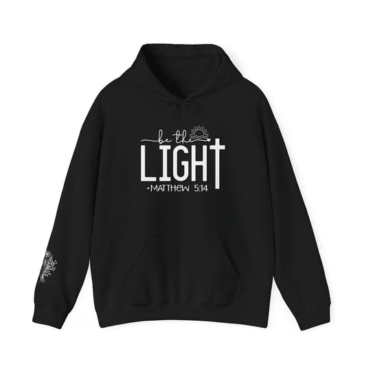 A black Be the Light Hoodie sweatshirt with white text, featuring a kangaroo pocket and drawstring hood. Unisex, 50% cotton, 50% polyester, medium-heavy fabric, classic fit, tear-away label.