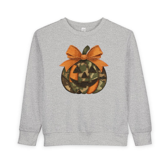Jackie O Toddler Crew: Light-gray sweatshirt with a camo-patterned jack-o-lantern graphic and stitched orange bow, offering cozy comfort for toddlers.