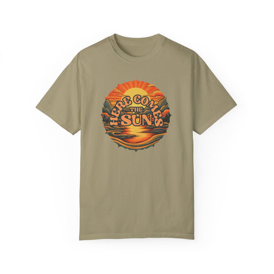 A tan tee with a graphic design, the Here Comes The Sun Tee from Worlds Worst Tees. 100% ring-spun cotton, garment-dyed for coziness, featuring a relaxed fit and durable double-needle stitching.