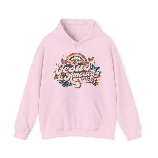 A pink She Loves Jesus and America hoodie with a graphic design, featuring a kangaroo pocket and drawstring hood. Unisex heavy blend fabric for comfort and warmth. Sizes S to 5XL available.