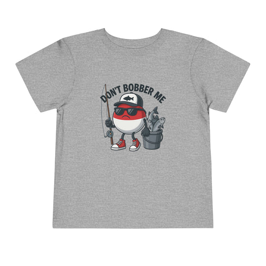 Cartoon bobber character on the Don't Bobber Me Toddler Tee, featuring sunglasses, cap, and fishing gear, perfect for adding humor to kids' wardrobes.