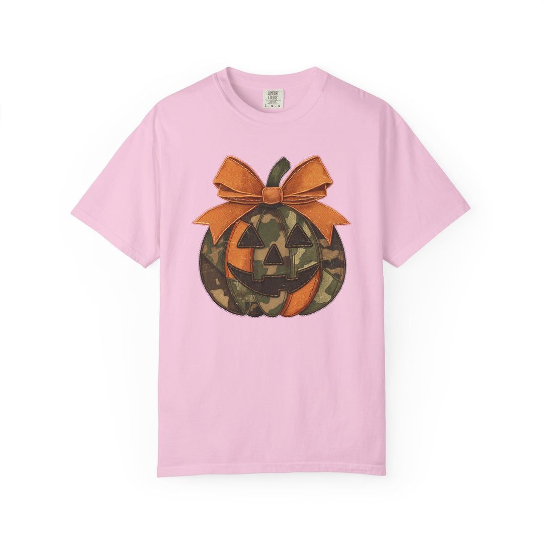 Jackie O Tee: Light pink crewneck T-shirt featuring a camo-patterned jack-o’-lantern graphic with triangular eyes, toothy smile, and large stitched orange bow.