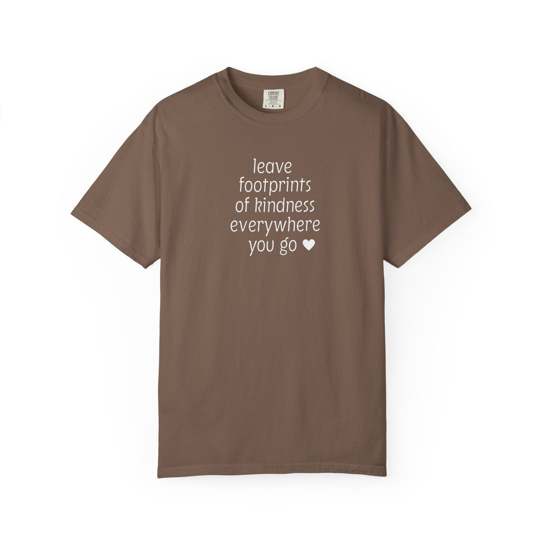 Leave Kindness Tee: Chocolate brown crew-neck T-shirt featuring the phrase “leave footprints of kindness everywhere you go ♥” in white, stacked lettering. Relaxed fit, soft-washed, durable.