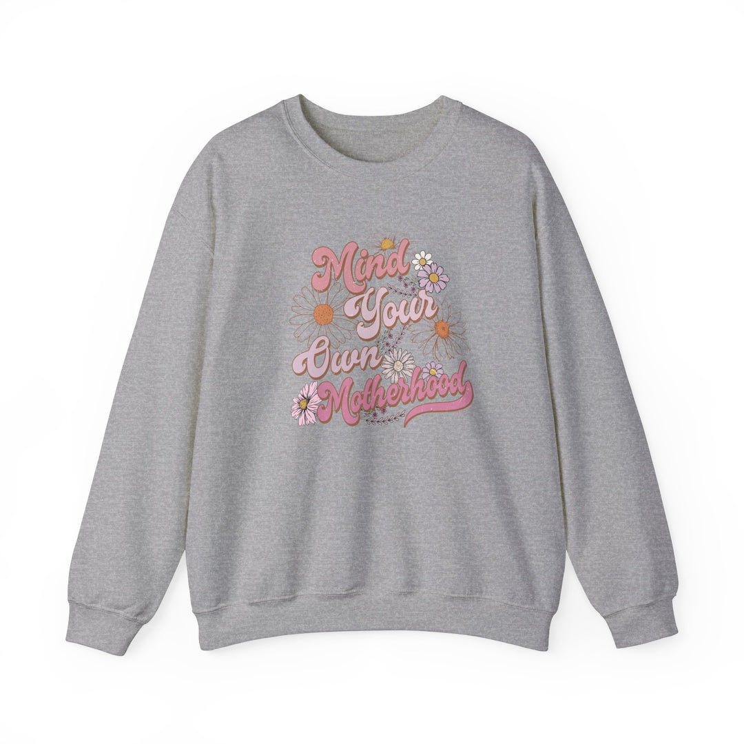 A unisex heavy blend crewneck sweatshirt, Mind Your Own Motherhood Crew, in grey with pink text. Made of 50% cotton, 50% polyester, ribbed knit collar, no itchy side seams, loose fit.