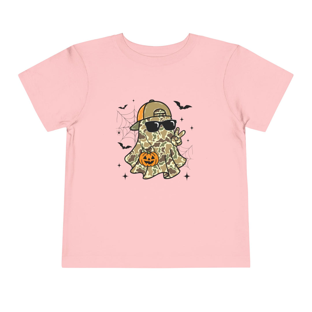 Candy Ghost Toddler Tee featuring a cartoon ghost in camouflage, wearing sunglasses and a cap, holding a peace sign and a jack-o’-lantern, surrounded by bats and spiderwebs.