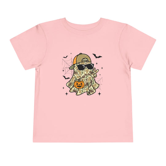 Candy Ghost Toddler Tee featuring a cartoon ghost in camouflage, wearing sunglasses and a cap, holding a peace sign and a jack-o’-lantern, surrounded by bats and spiderwebs.