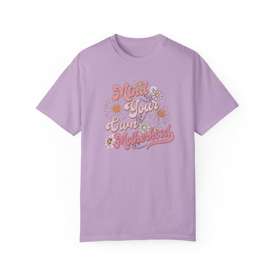 A Mind Your Motherhood Tee: Purple shirt with flowers and text. 100% ring-spun cotton, garment-dyed for extra coziness. Relaxed fit, durable double-needle stitching, tubular shape. Sizes S-4XL.