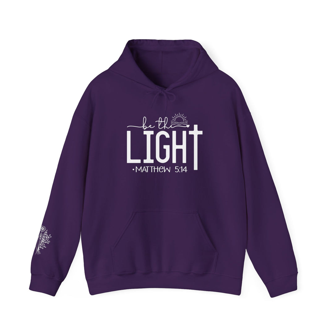 A cozy unisex Be the Light Hoodie in purple, featuring white text, a kangaroo pocket, and matching drawstring. Made of 50% cotton and 50% polyester for warmth and comfort. Ideal for chilly days.