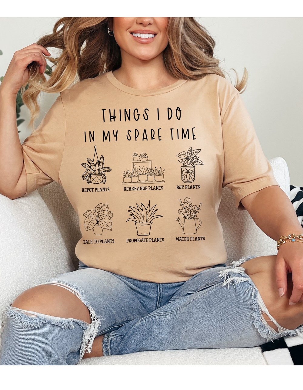 Person seated on a couch wearing the Plants Spare Time Tee, featuring icons and captions about plant activities. The tee reflects a humorous, plant-themed design.