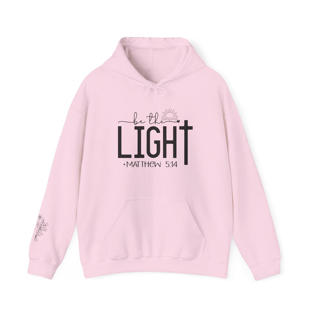 A pink unisex Be the Light Hoodie with black text, featuring a kangaroo pocket and matching drawstring. Made of 50% cotton and 50% polyester, offering warmth and comfort for cold days.