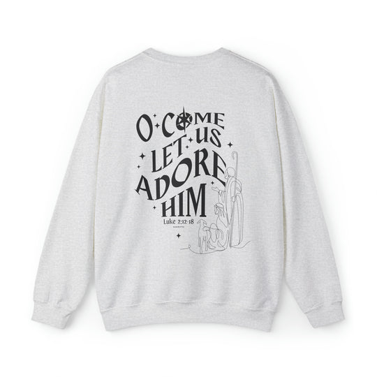 A white crewneck sweatshirt with black text, featuring the design O come let us adore him Crew. Unisex, heavy blend fabric, ribbed knit collar, no itchy side seams. Sizes S-5XL.