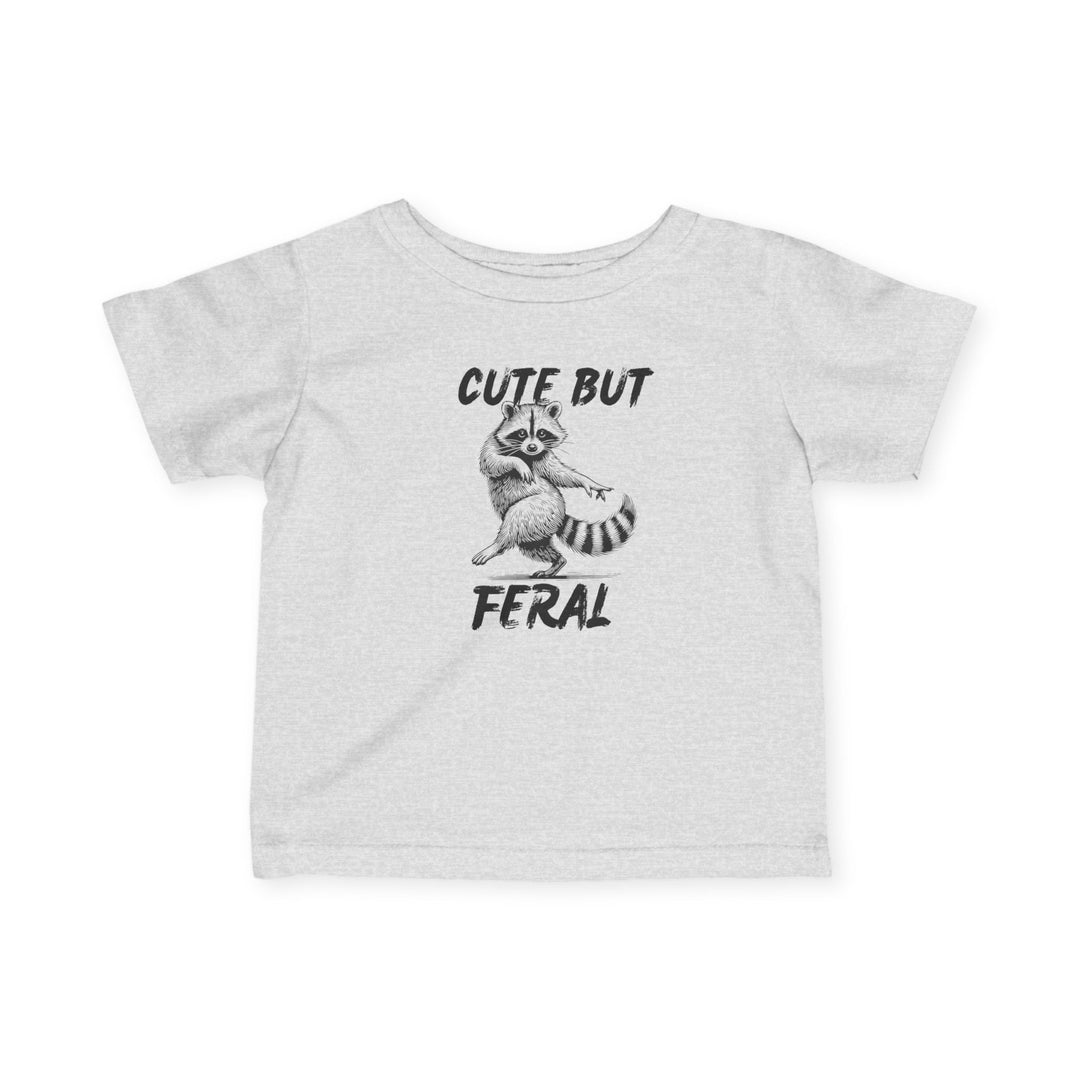 Cute but Feral Baby Tee featuring a playful, dancing raccoon graphic and bold text; designed for toddlers, offering comfort and durability with a classic fit.