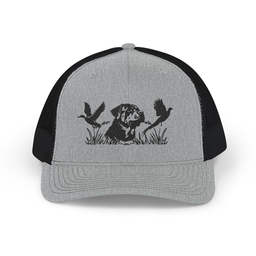 Bird Hunting Snapback Trucker Cap featuring a stamped dog silhouette amidst marsh grass with flying waterfowl, gray front, black mesh back, adjustable snap closure.
