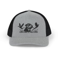 Bird Hunting Snapback Trucker Cap featuring a stamped dog silhouette amidst marsh grass with flying waterfowl, gray front, black mesh back, adjustable snap closure.