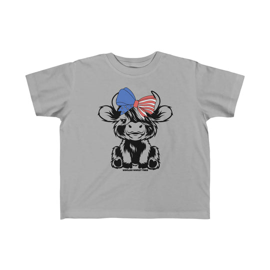 Toddler tee featuring a cartoon cow with a blue bow, ideal for sensitive skin. 100% combed ringspun cotton, light fabric, tear-away label, classic fit. Perfect for 4th of July family fun.