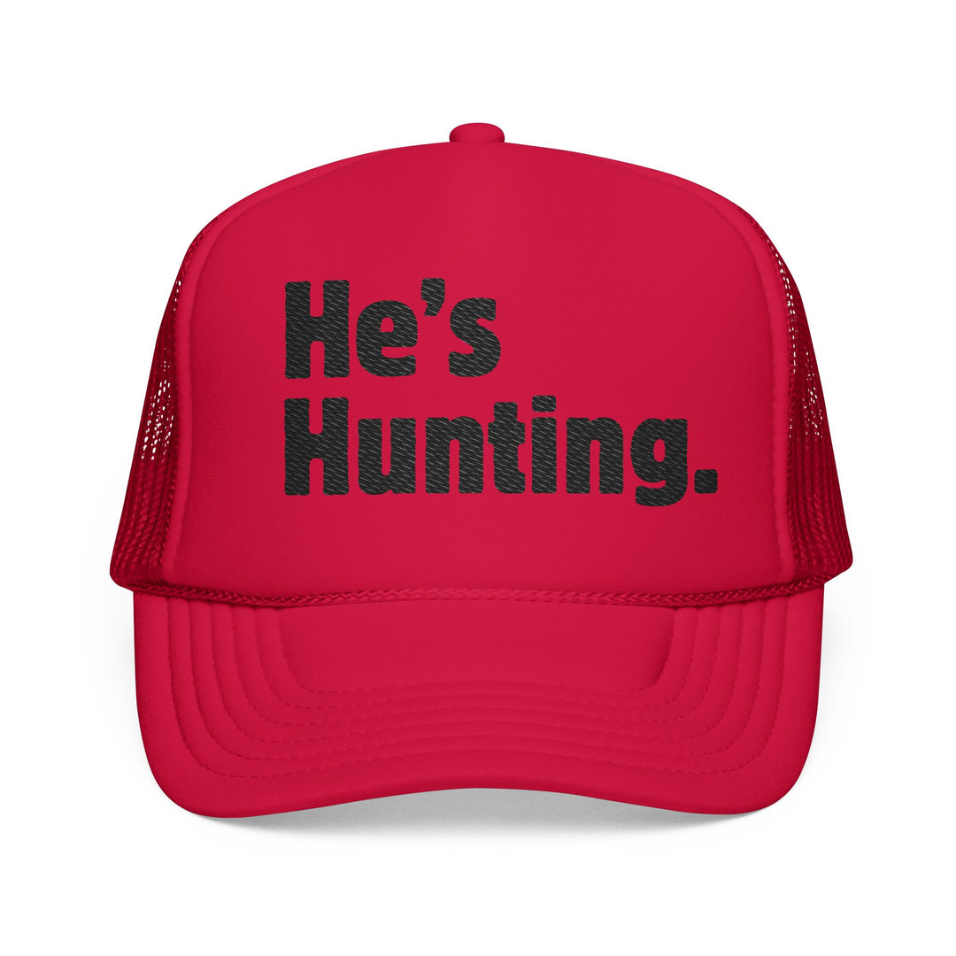 Red trucker-style cap with He's Hunting. in bold black letters on the front, featuring mesh back, flat bill, and adjustable snap closure.