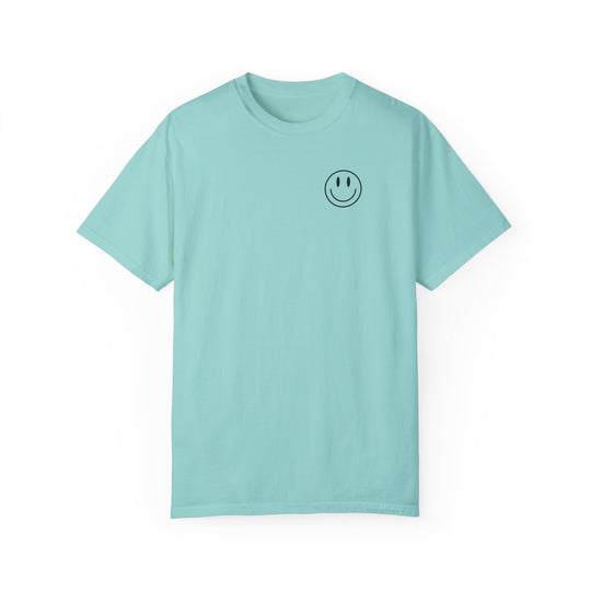 A light blue tee with a smiley face graphic, the God Day to Have a Good Day Tee. 100% ring-spun cotton, garment-dyed for extra coziness and durability, featuring a relaxed fit and double-needle stitching.