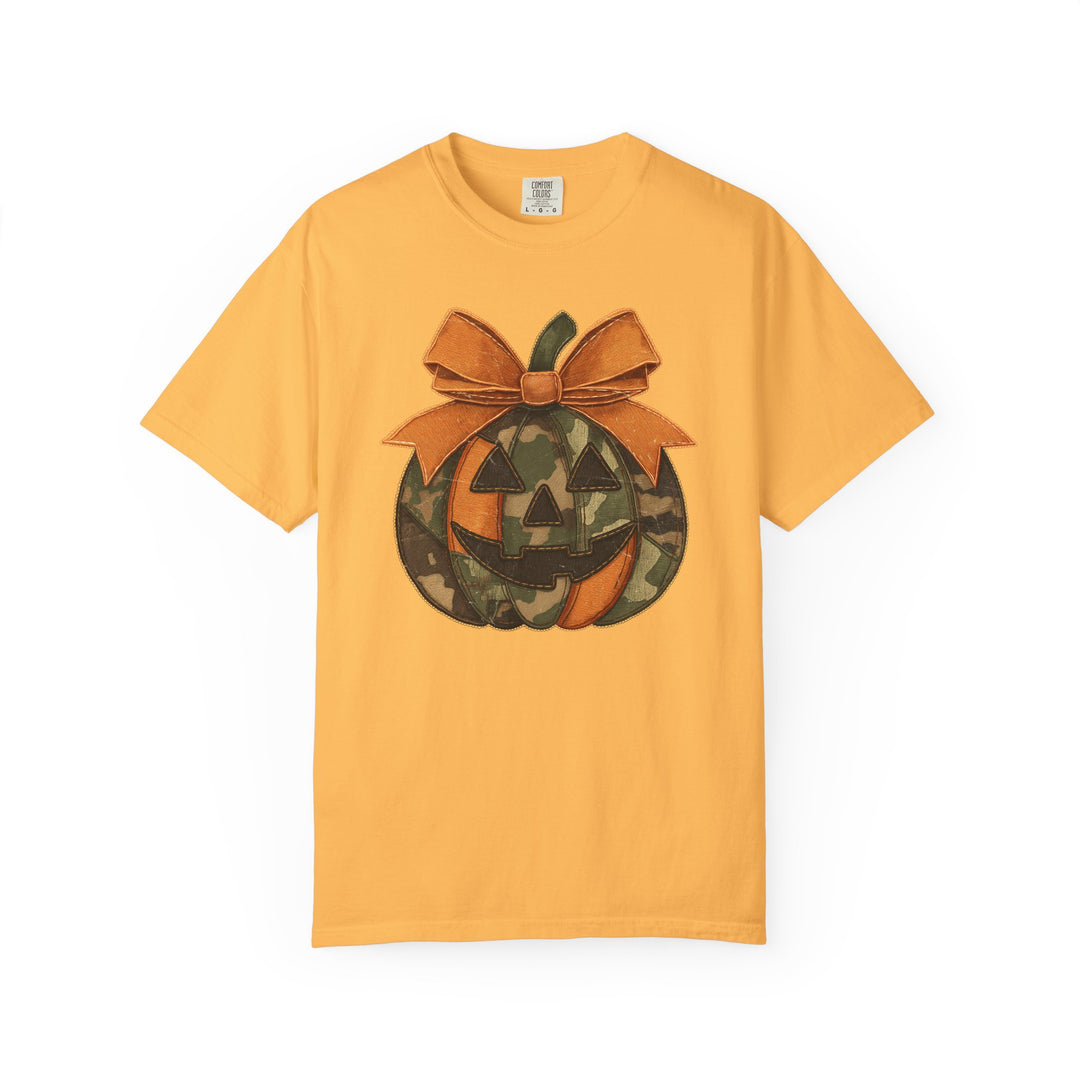 Mustard-yellow Jackie O Tee featuring a jack-o-lantern with orange and camouflage segments, topped with an orange bow. Comfortable, durable, and perfect for casual wear.