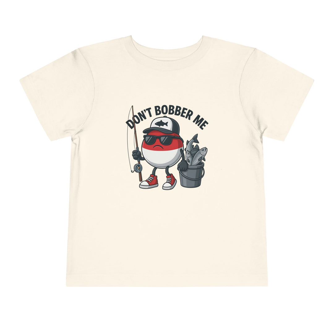 Cartoon fishing bobber character with sunglasses and cap on light T-shirt, holding rod and fish bucket. Slogan: DON’T BOBBER ME. Toddler sizes available.