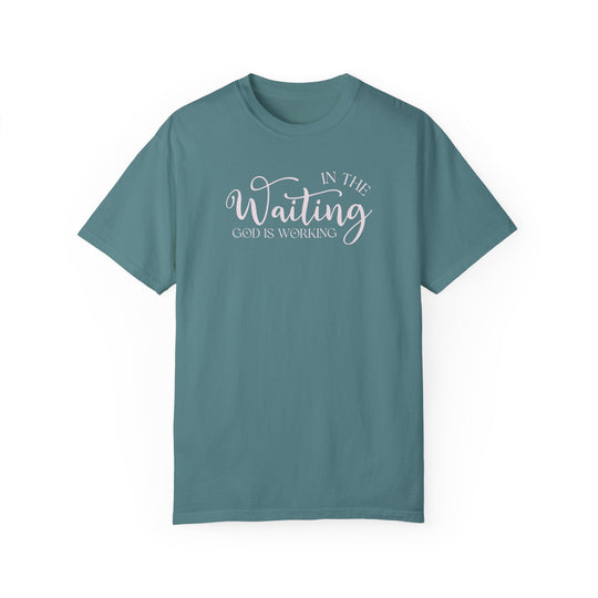Relaxed fit God is Working Tee, garment-dyed in blue with white text. 100% ring-spun cotton, soft-washed for coziness, double-needle stitching for durability, no side-seams for tubular shape.