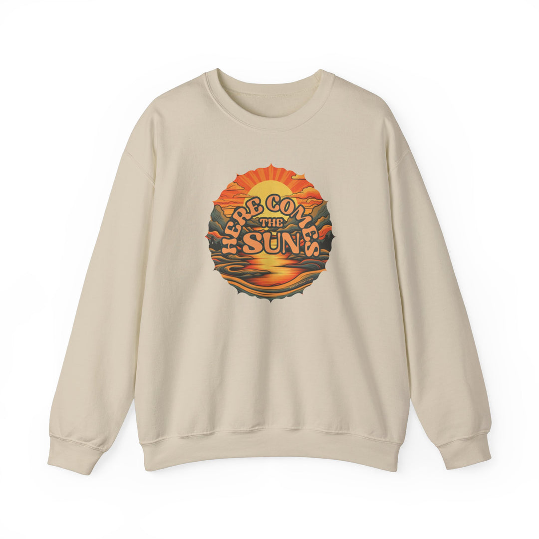 A tan crewneck sweatshirt with a graphic sunset and mountain design, ideal for comfort. Unisex heavy blend, 50% cotton 50% polyester, loose fit, ribbed knit collar, no itchy seams. Here Comes the Sun Crew by Worlds Worst Tees.