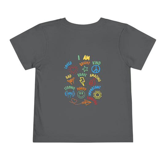 I AM Toddler Tee: Dark-gray shirt featuring colorful doodles and affirmations like LOVED, BRAVE, and HAPPY, with matching icons, made from soft, comfortable cotton.