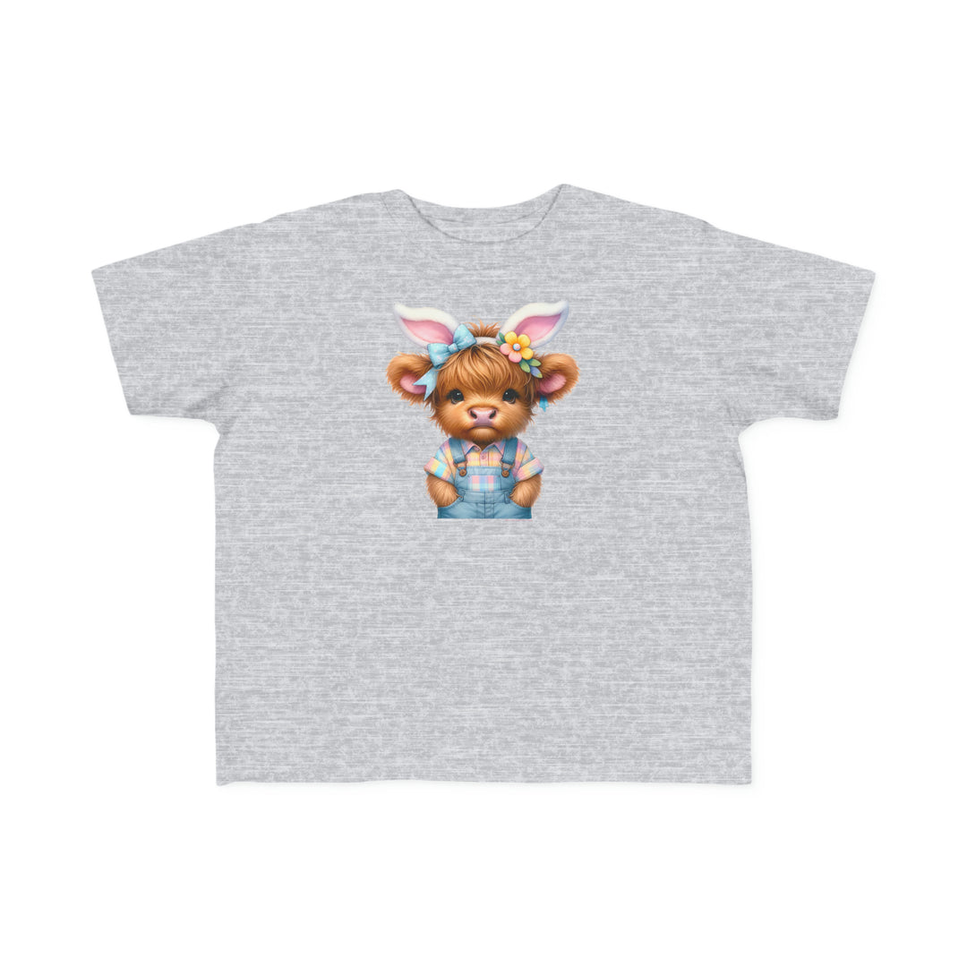 A grey toddler tee featuring a cartoon cow with bunny ears, ideal for sensitive skin. Made of 100% combed ringspun cotton, light fabric, classic fit, and tear-away label. Title: Easter Cow Toddler Tee.
