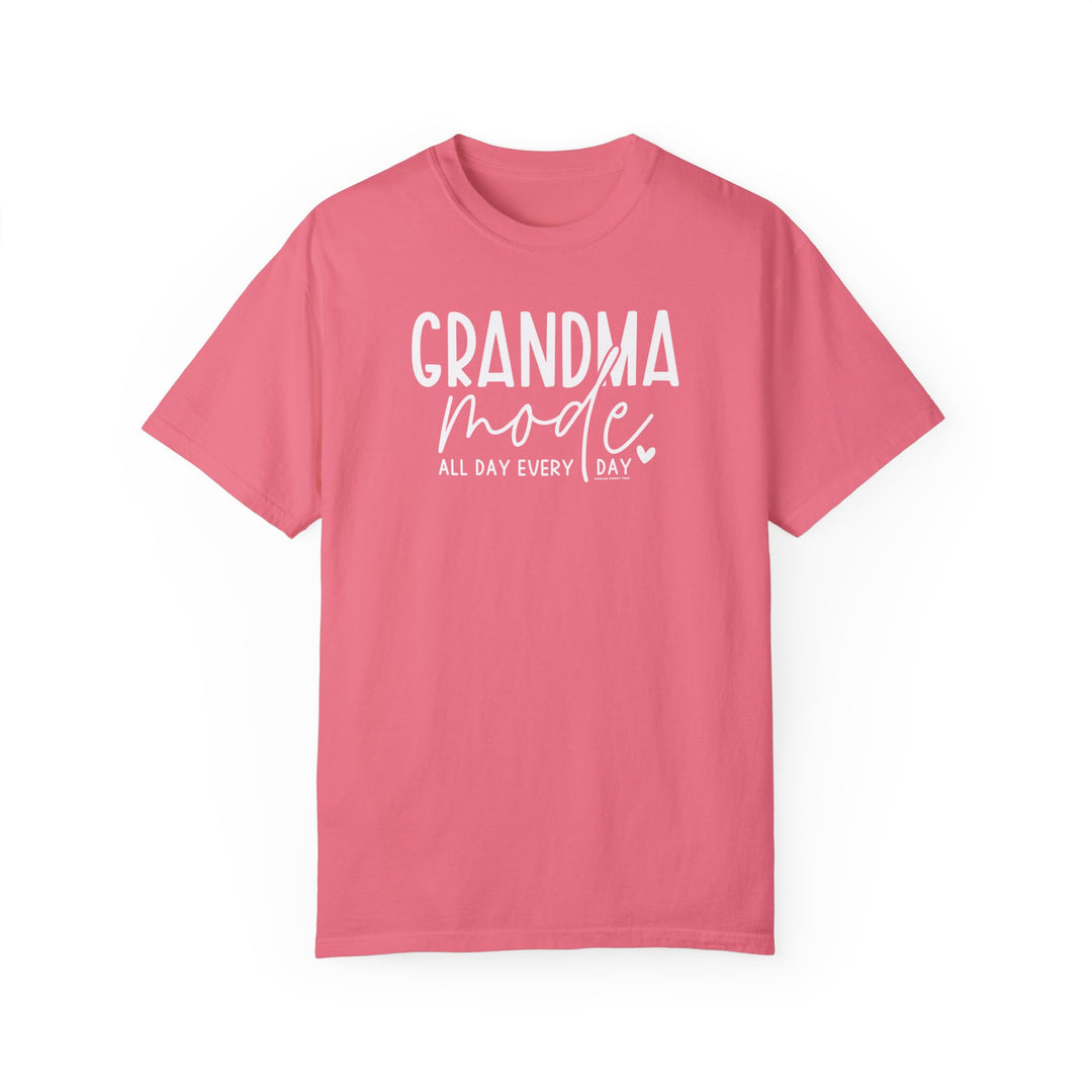 A Grandma Mode Tee: Pink shirt with white text. 100% ring-spun cotton, garment-dyed for coziness. Relaxed fit, durable double-needle stitching, tubular shape. Ideal for daily wear.