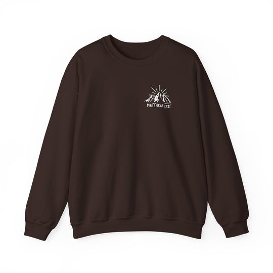 A brown Faith Can Move Mountains Crew sweatshirt with a logo of a mountain and sun. Unisex heavy blend crewneck made of 50% cotton and 50% polyester, featuring ribbed knit collar and double-needle stitching for durability.