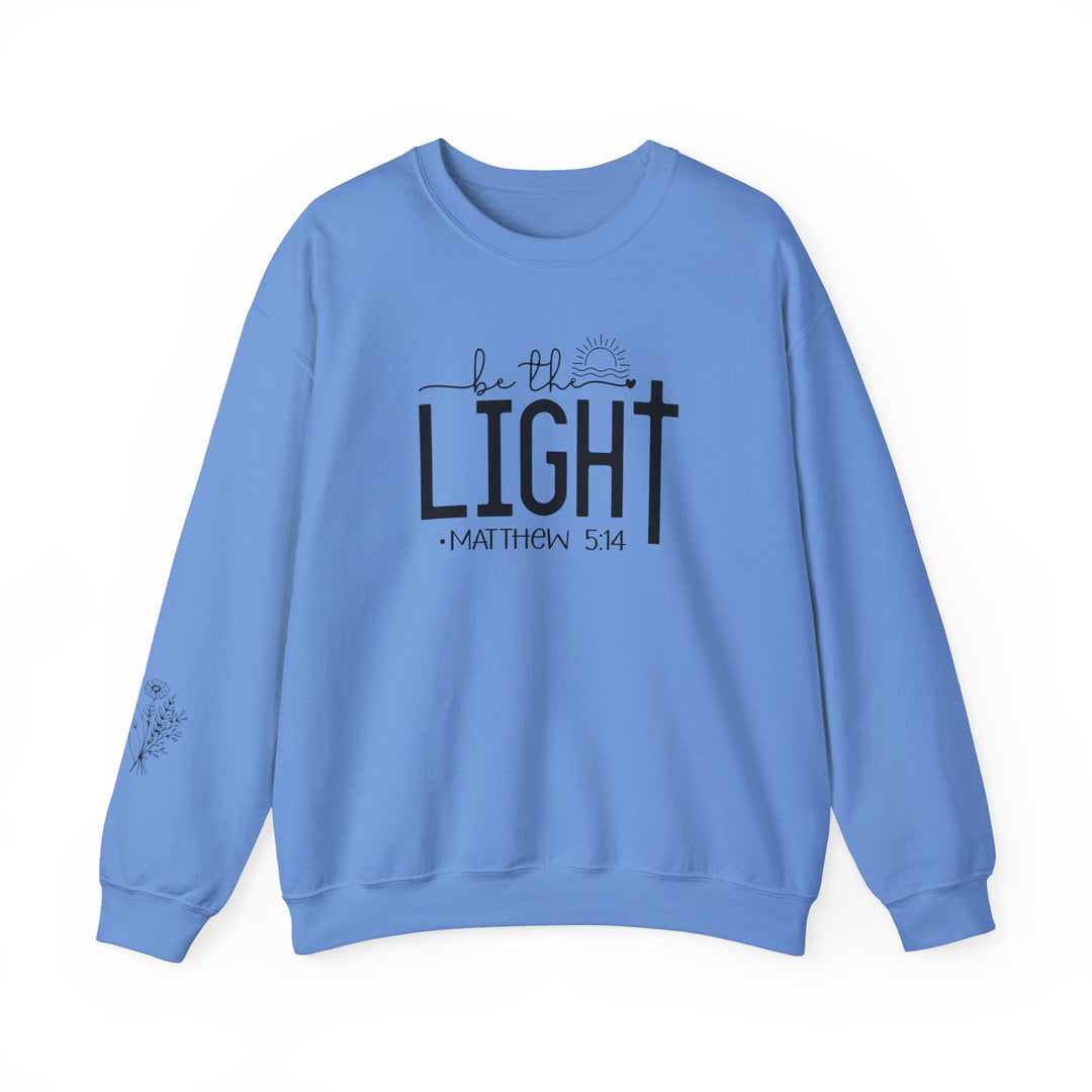 Unisex heavy blend crewneck sweatshirt, Be the Light Crew, in blue with black text. Made of 50% cotton, 50% polyester fabric for cozy warmth. Ribbed knit collar, double-needle stitching for durability, tear-away label for comfort.