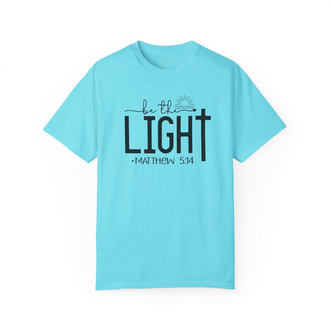 A cozy Be the Light Tee in light blue with black text. 100% ring-spun cotton, garment-dyed, relaxed fit, durable double-needle stitching, seamless design for comfort. Ideal for daily wear.