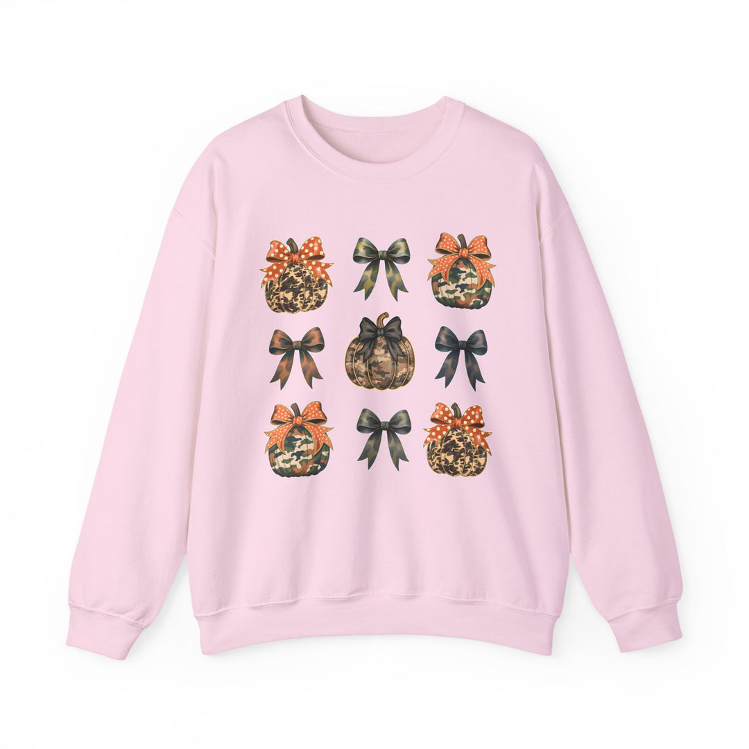 Light-pink crewneck sweatshirt featuring a 3x3 grid of camo-patterned pumpkins and bows, blending comfort and seasonal style in a unique design.