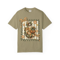 Quilted Ghost Tee features a ghost with a patchwork sheet and bow, holding a jack-o-lantern, framed by curly vines and flowers.