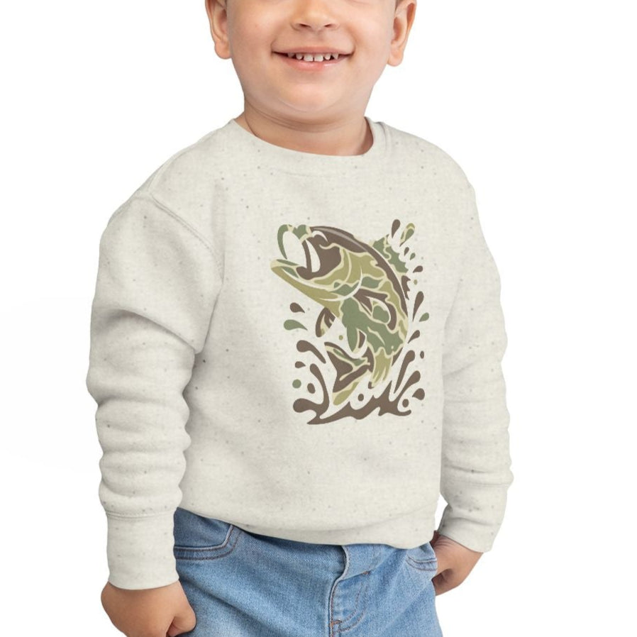 Toddler wearing a Camo Fish Toddler Crew sweatshirt featuring a jumping bass, smiling with one hand in jeans pocket, showcasing comfort and playful design.