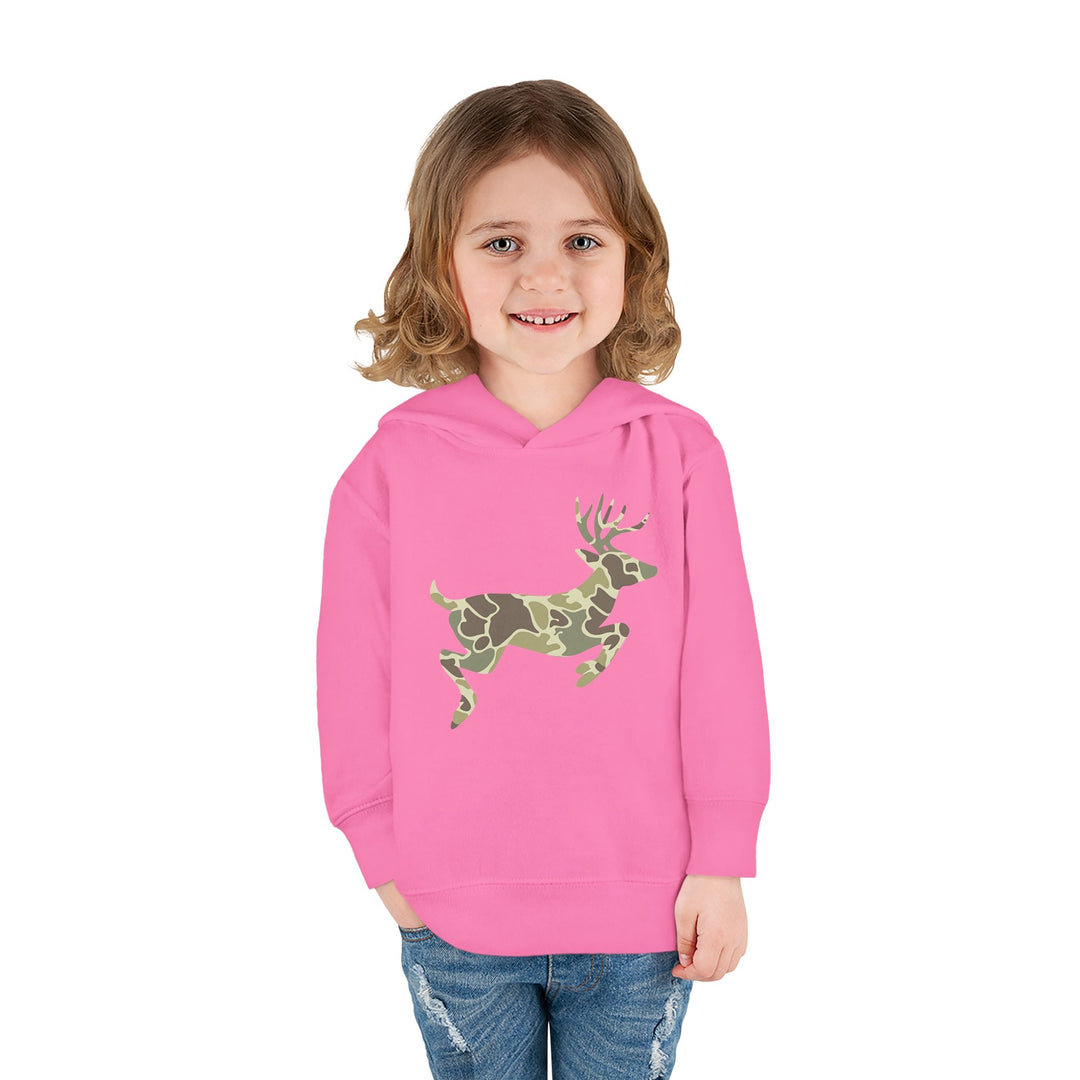 Toddler in a Camo Deer Toddler Hoodie with side-seam pockets, smiling, showcasing the jersey-lined hood and durable design, paired with blue jeans against a white background.