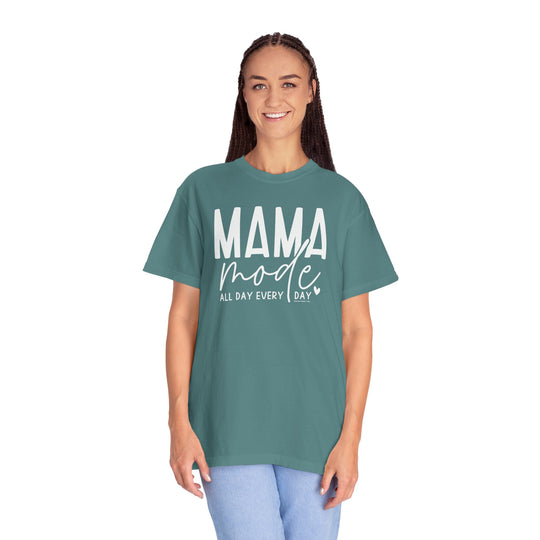 Alt text: Mama Mode Tee: A woman in a green garment-dyed t-shirt, showcasing a relaxed fit and ring-spun cotton fabric. Double-needle stitching ensures durability, while the lack of side-seams maintains a sleek silhouette.