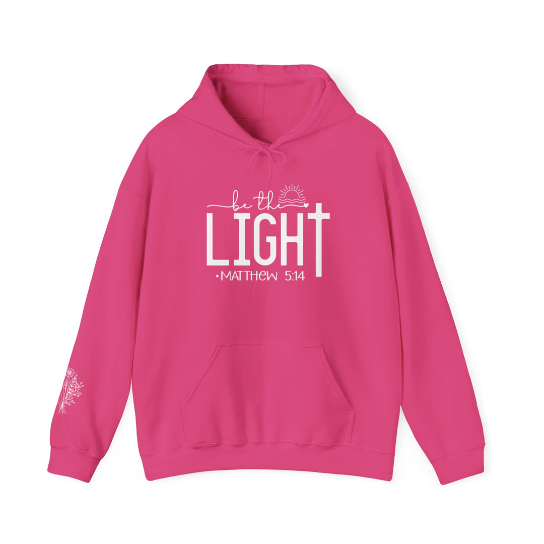 A cozy unisex Be the Light Hoodie in pink with white text. Made of 50% cotton, 50% polyester, featuring a kangaroo pocket and matching drawstring hood. Perfect for chilly days.