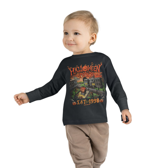 A toddler wearing a black long-sleeve tee with a graphic design, made of 100% combed ringspun cotton. Features topstitched ribbed collar and EasyTear™ label for comfort and durability. From 'Worlds Worst Tees'.