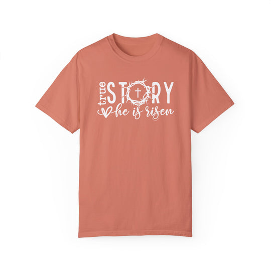 A ring-spun cotton True Story He is Risen Tee, featuring a cross and crown design on a pink background. Relaxed fit, double-needle stitching, and no side-seams for durability and comfort.