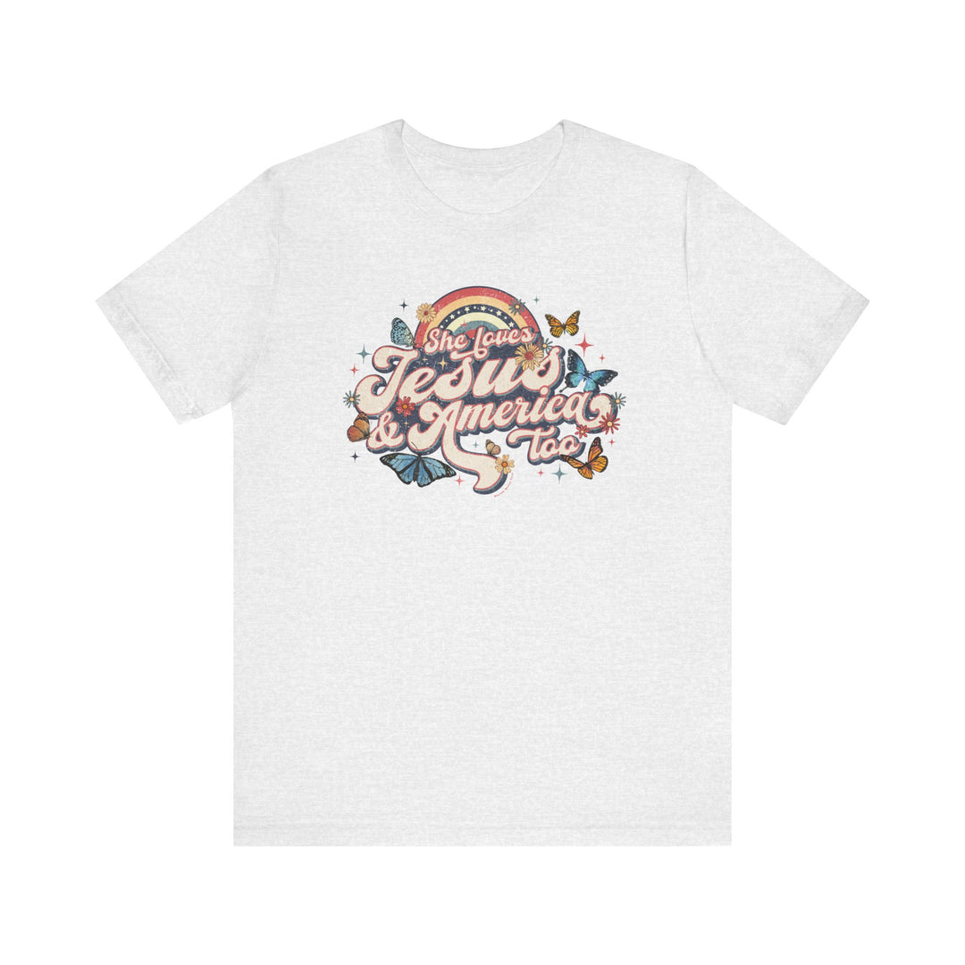 A white t-shirt featuring a graphic design of butterflies and flowers, titled She Loves Jesus and America Tee. Unisex jersey tee made of 100% Airlume combed cotton, with ribbed knit collars, taping on shoulders, and tear-away label.