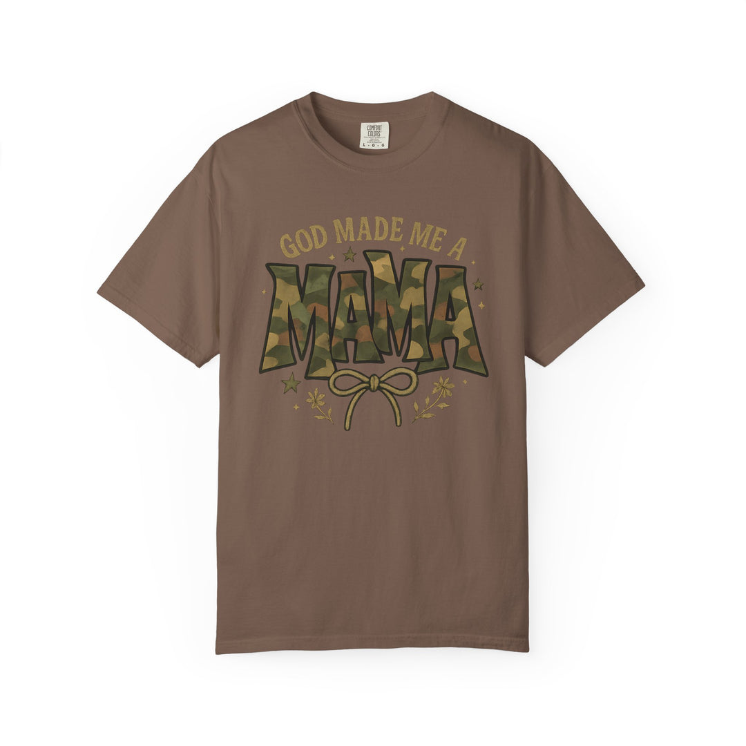 God Made Me a Mama Tee features a camouflage-patterned MAMA graphic with bow and floral accents on a brown, short-sleeve, relaxed-fit, cotton shirt.