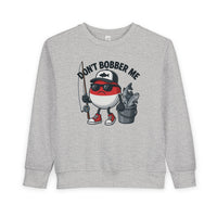 Don't Bobber Me Toddler Crew sweatshirt with cartoon bobber character, sunglasses, cap, holding fishing gear. Cozy, durable, perfect for toddler style and comfort.