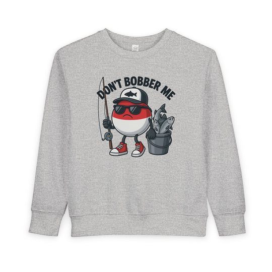 Don't Bobber Me Toddler Crew sweatshirt with cartoon bobber character, sunglasses, cap, holding fishing gear. Cozy, durable, perfect for toddler style and comfort.
