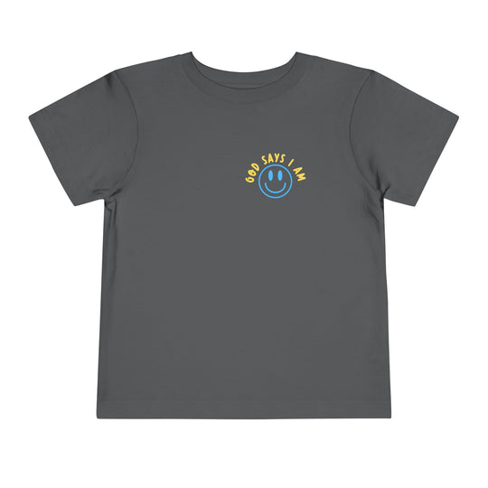 I AM Toddler Tee: Dark gray, short-sleeved T-shirt featuring a smiling face graphic and GOD SAYS I AM text on the chest. Made from soft cotton.